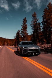 a silver sports car driving down a road