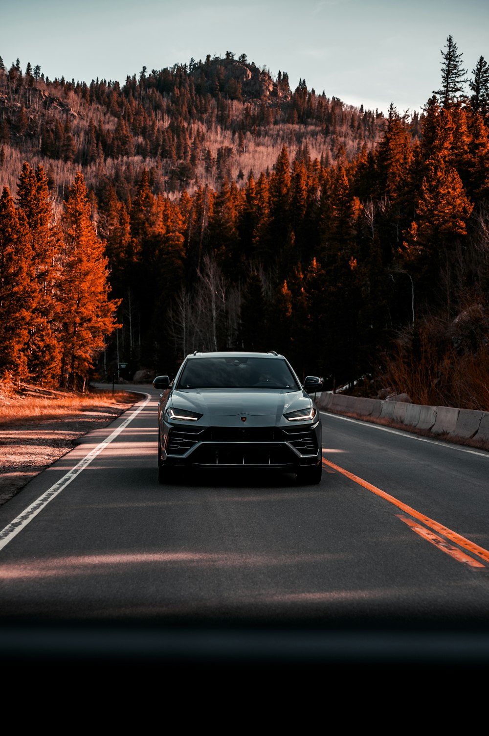 a car driving down a road with a mountain in the background