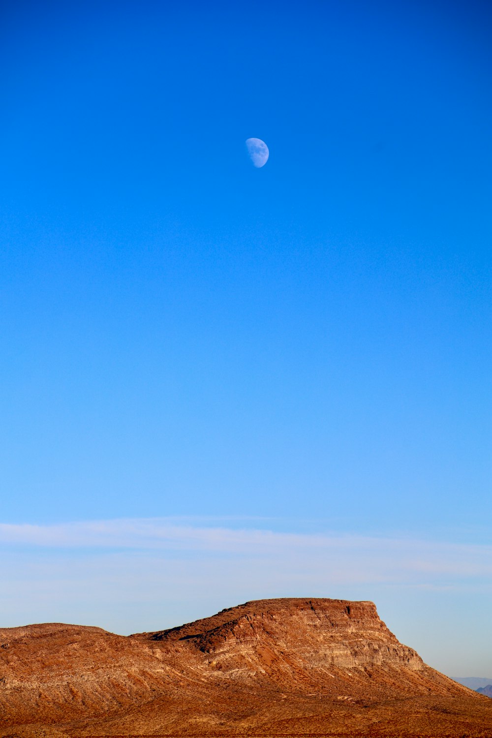 a hill with a half moon in the sky