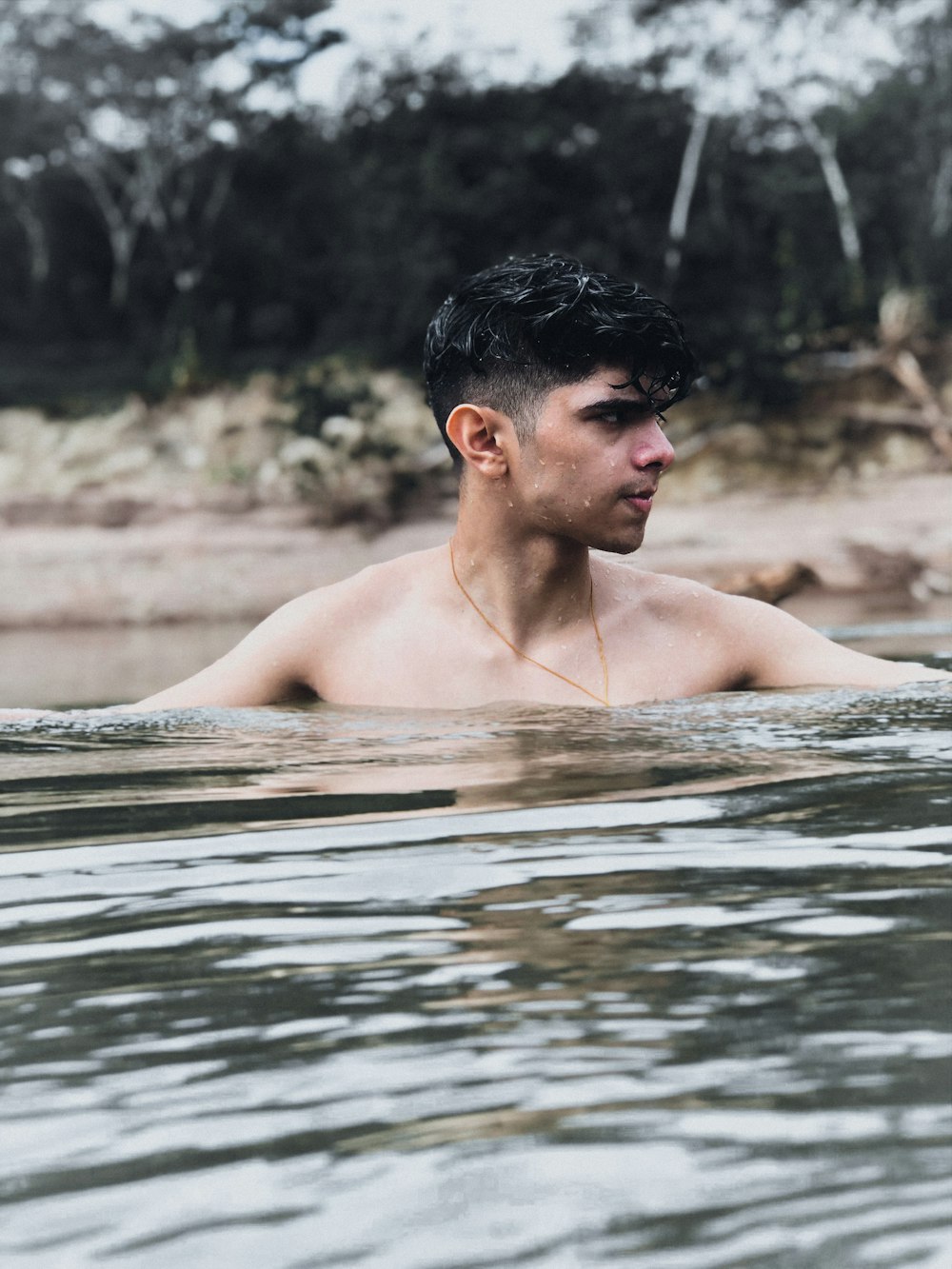 a man in a body of water with trees in the background