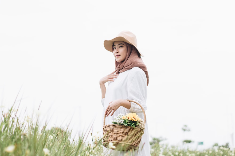 a woman in a white dress and hat holding a basket