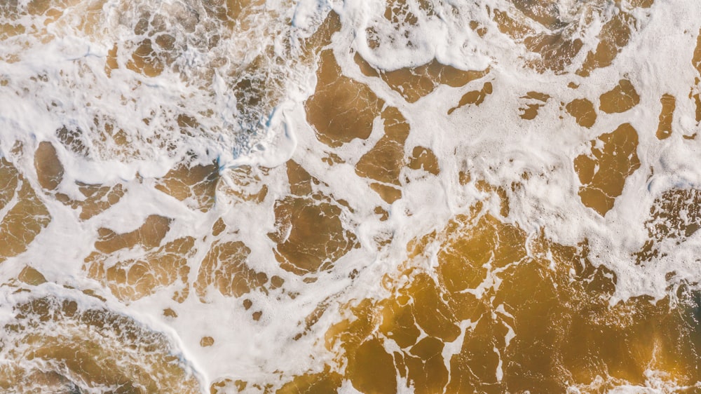 an aerial view of the ocean waves and sand