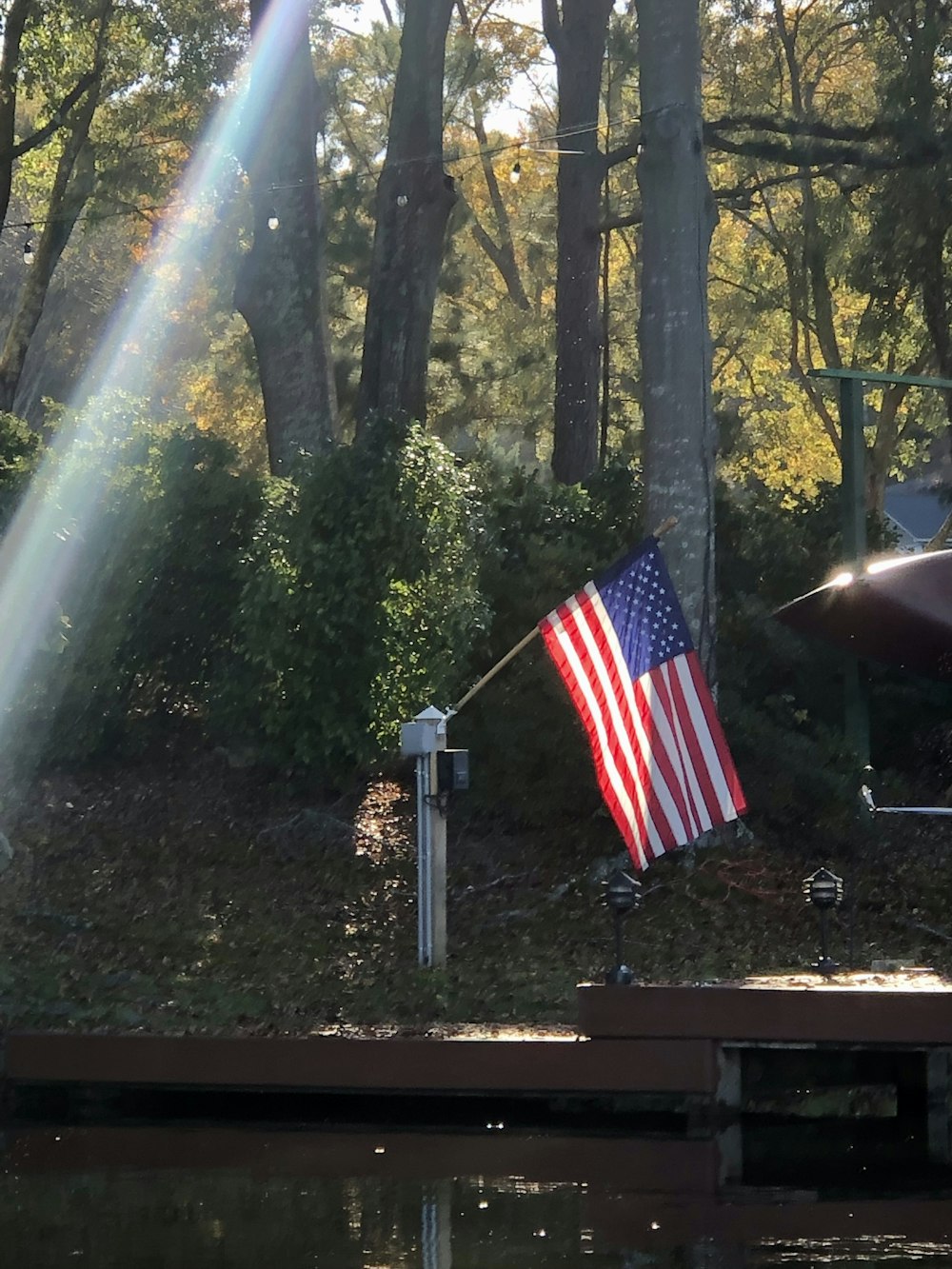 an american flag on a pole next to a body of water