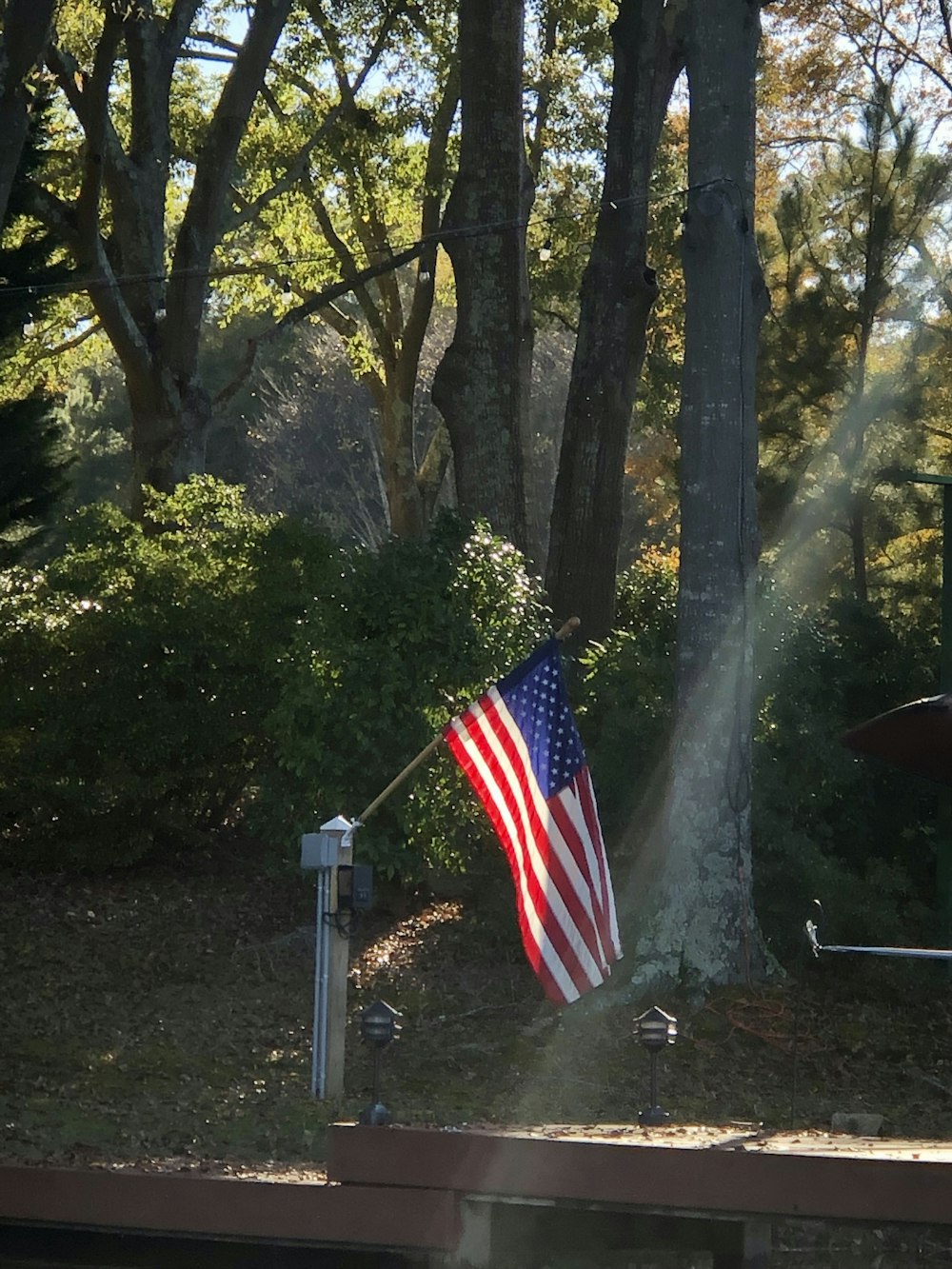 an american flag on a pole in front of some trees