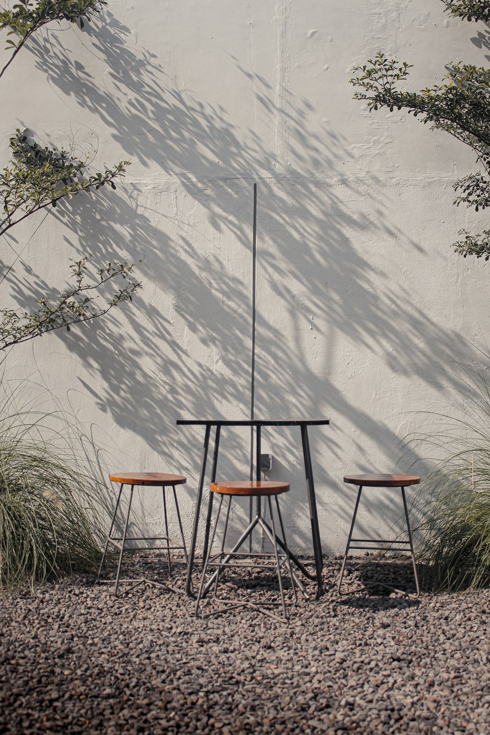 three chairs and a table in front of a white wall