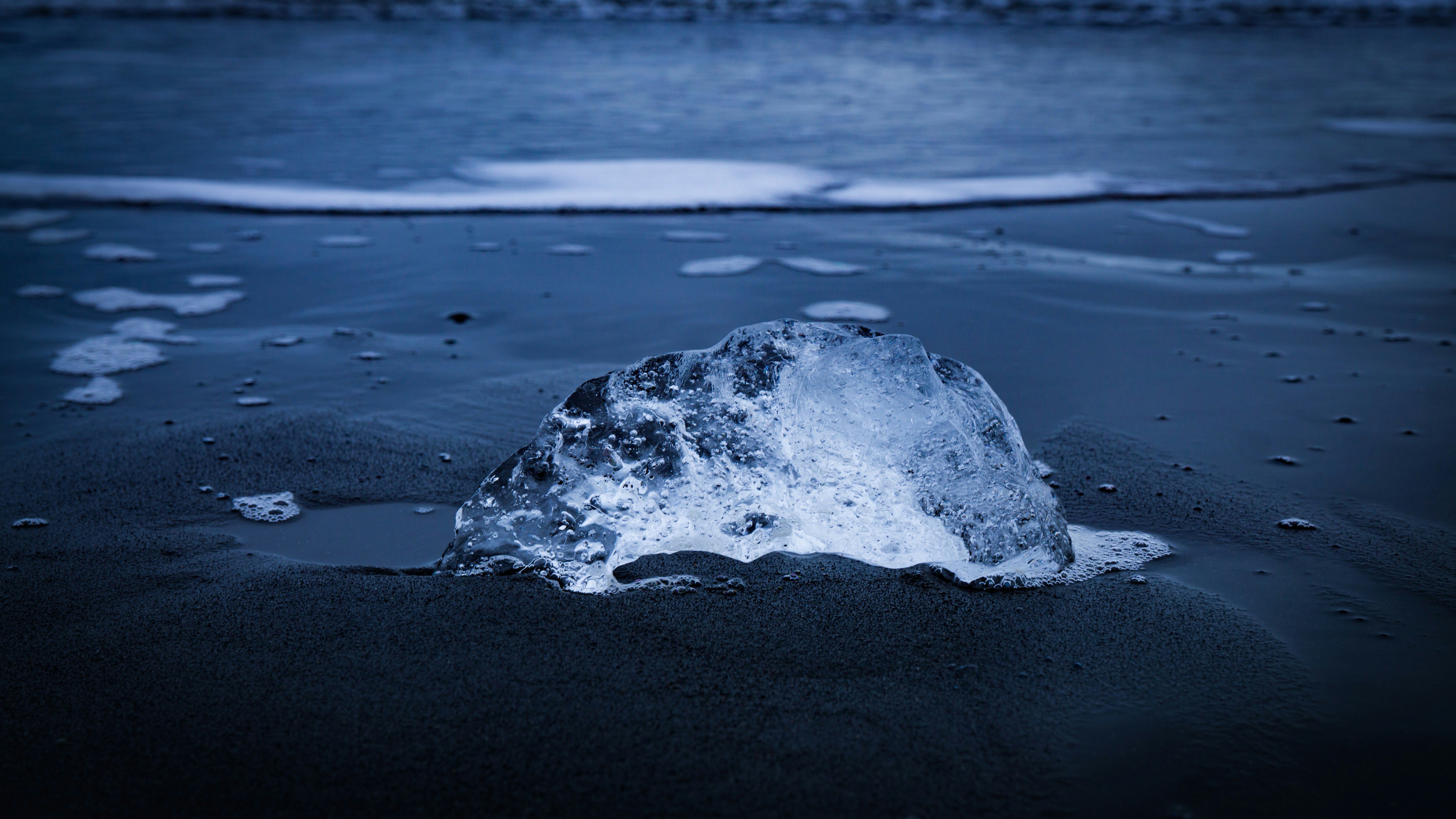 an iceberg on a beach with water in the background