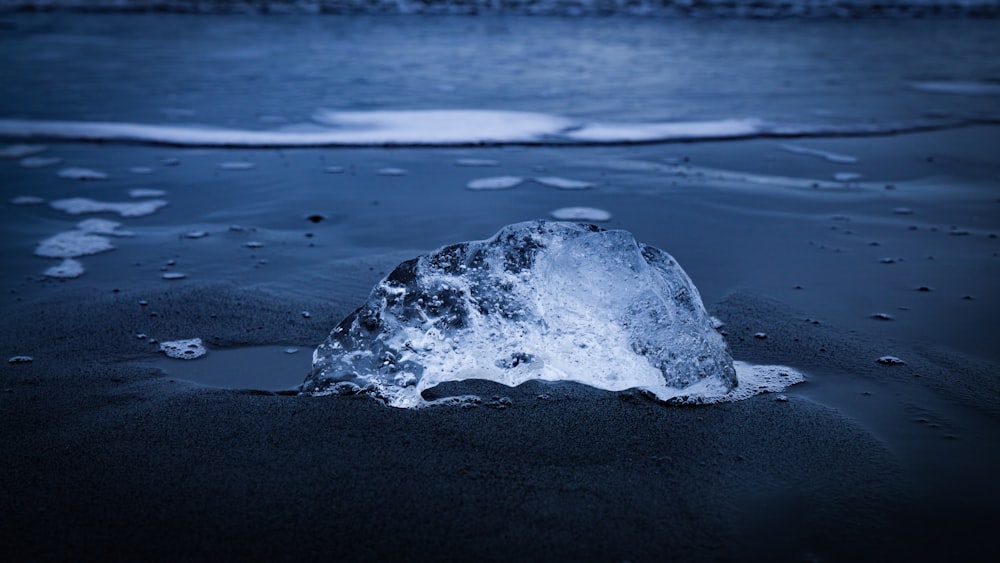 an iceberg on a beach with water in the background