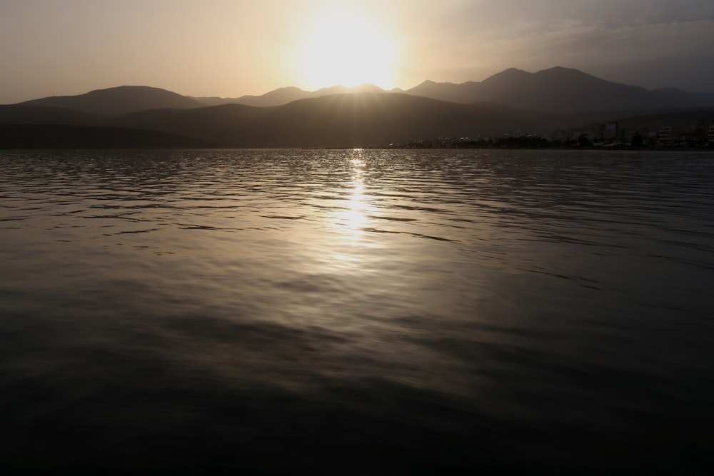 a large body of water with a sunset in the background