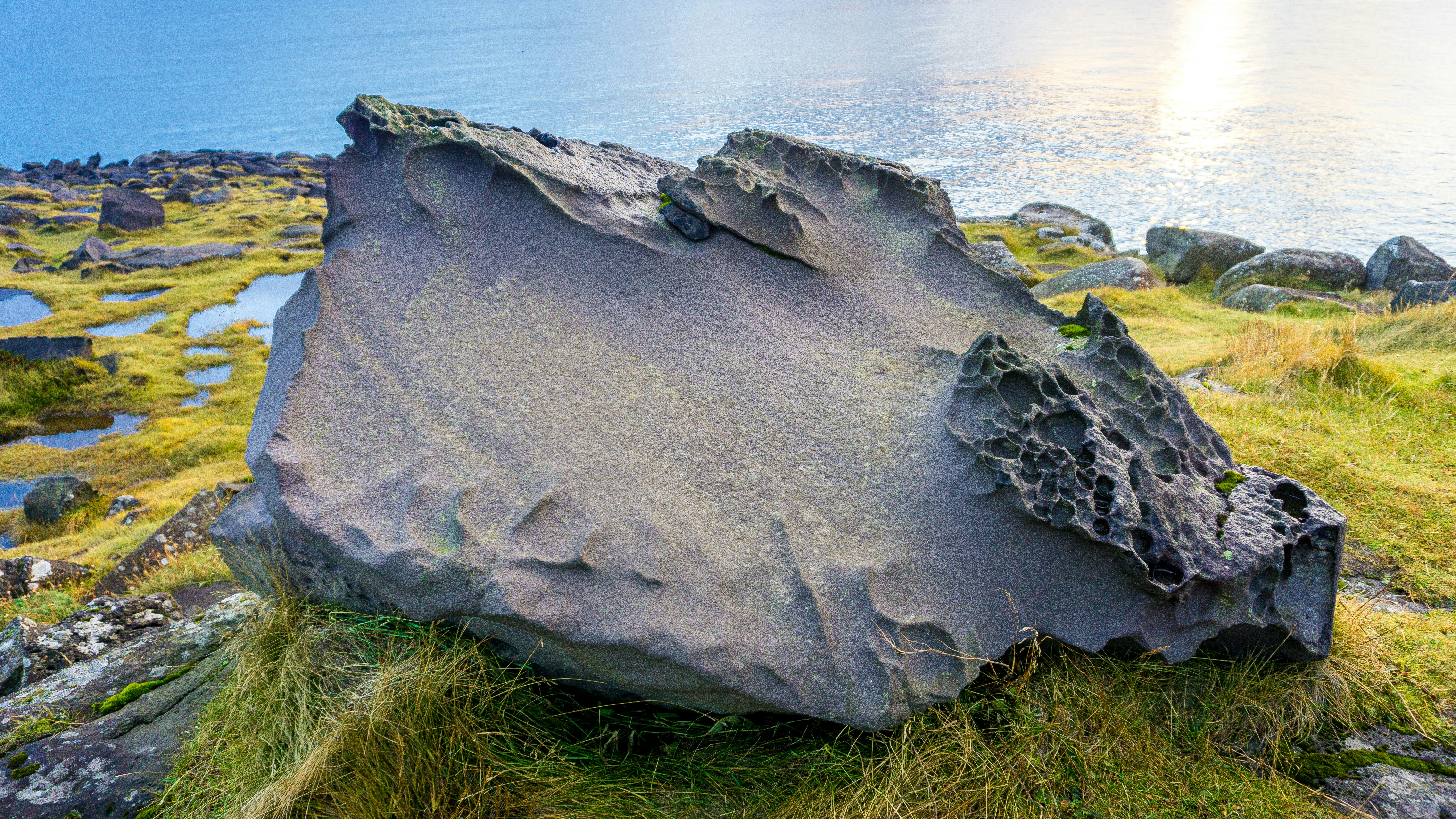 a large rock sitting on top of a lush green hillside