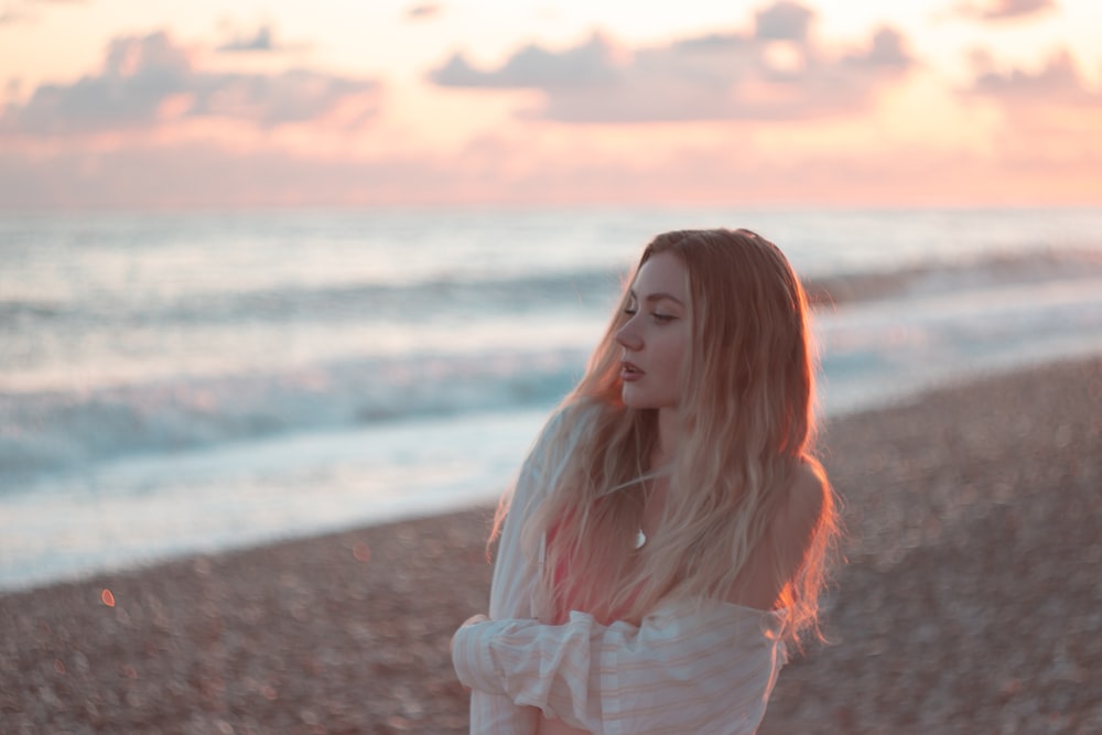 a woman standing on top of a beach next to the ocean