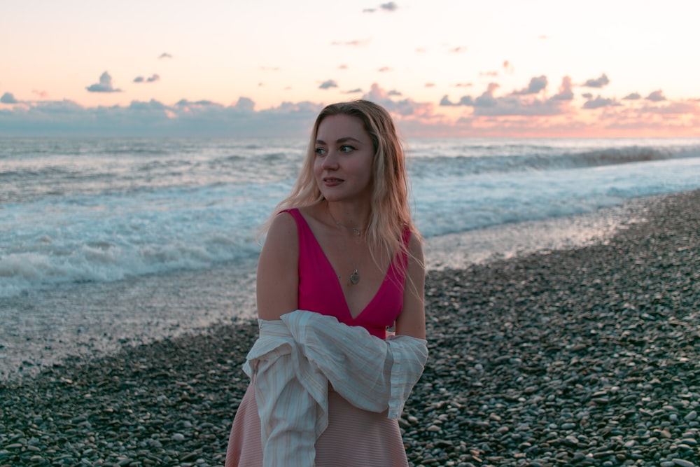 a woman standing on a beach next to the ocean