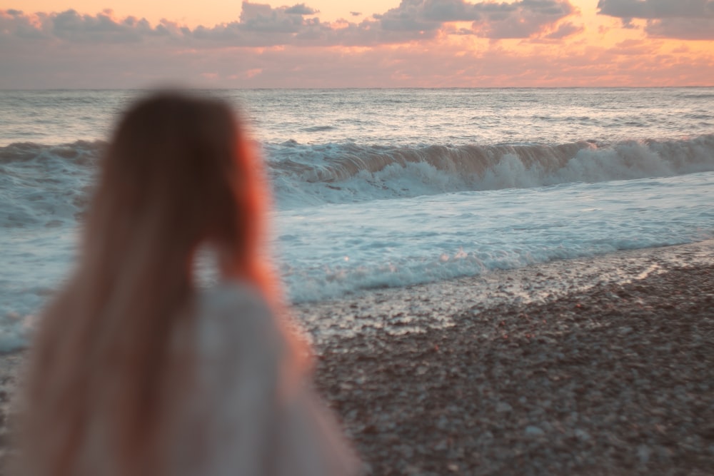 a woman standing on a beach next to the ocean