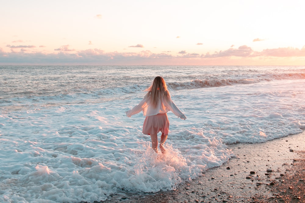 a woman standing in the surf at the beach