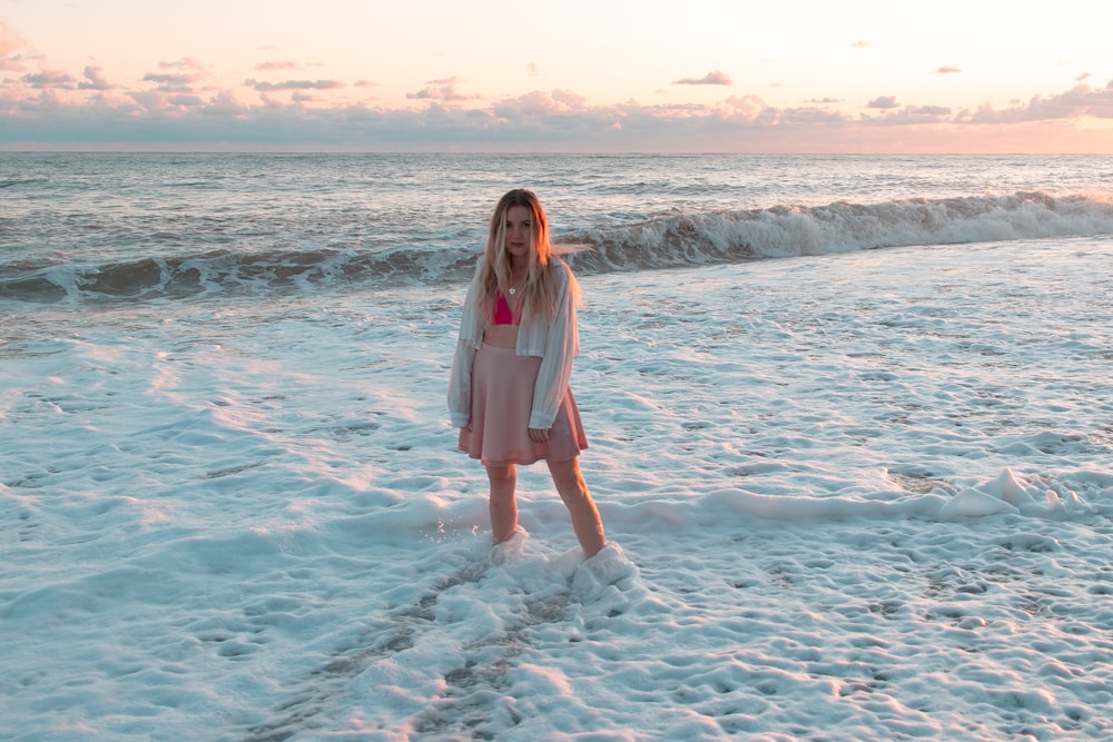 a woman standing on a beach next to the ocean