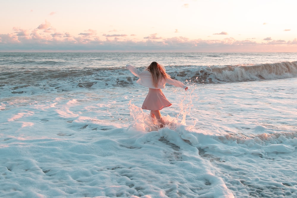 a woman in a pink dress standing in the ocean