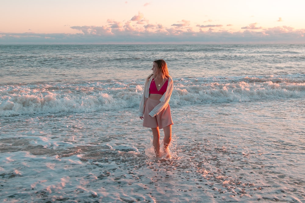 a woman in a pink bikini walking into the ocean