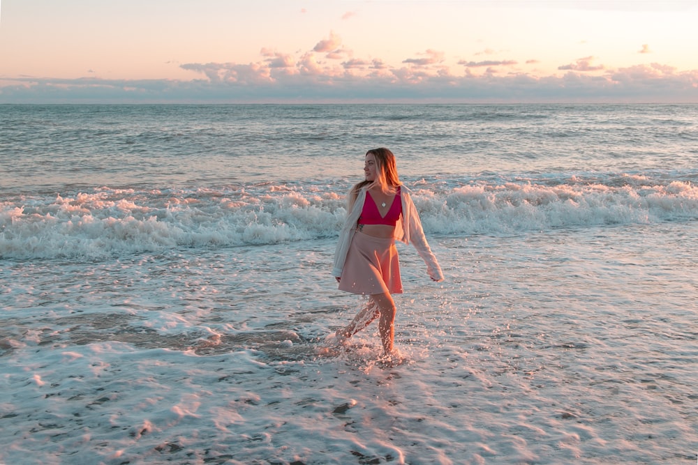a woman in a pink bikini walking into the ocean