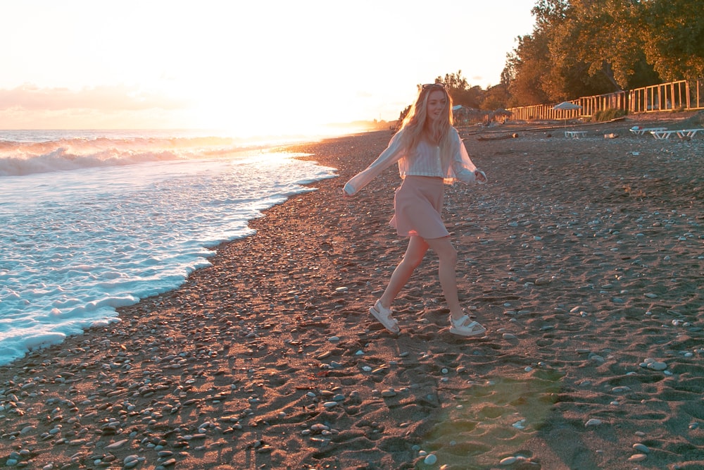 a woman walking along a beach next to the ocean