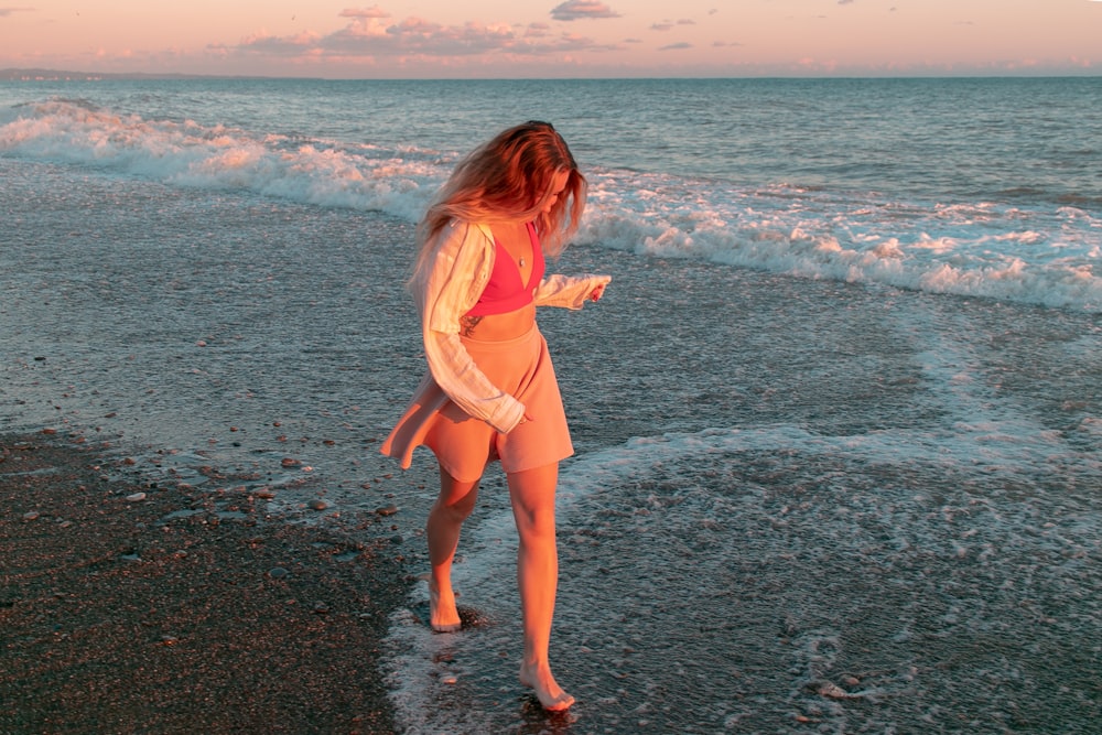 a woman standing on a beach next to the ocean