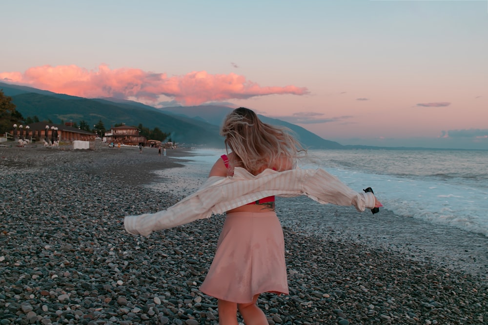 a woman is walking on a rocky beach