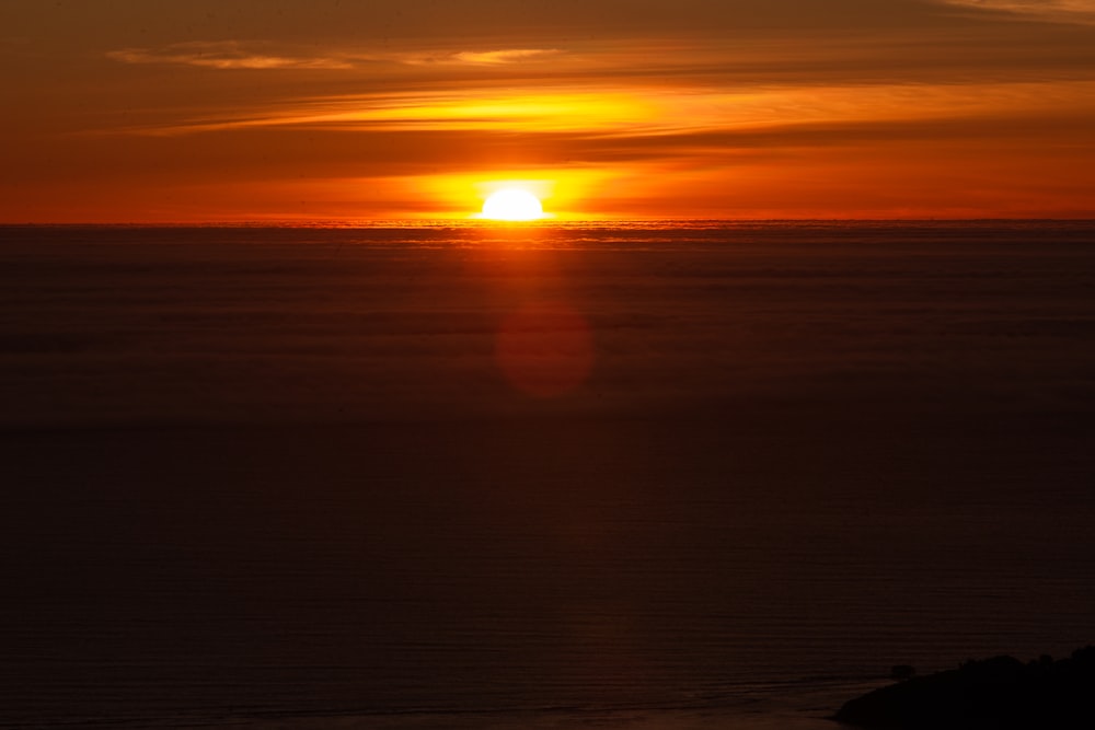 the sun is setting over the ocean on a cloudy day