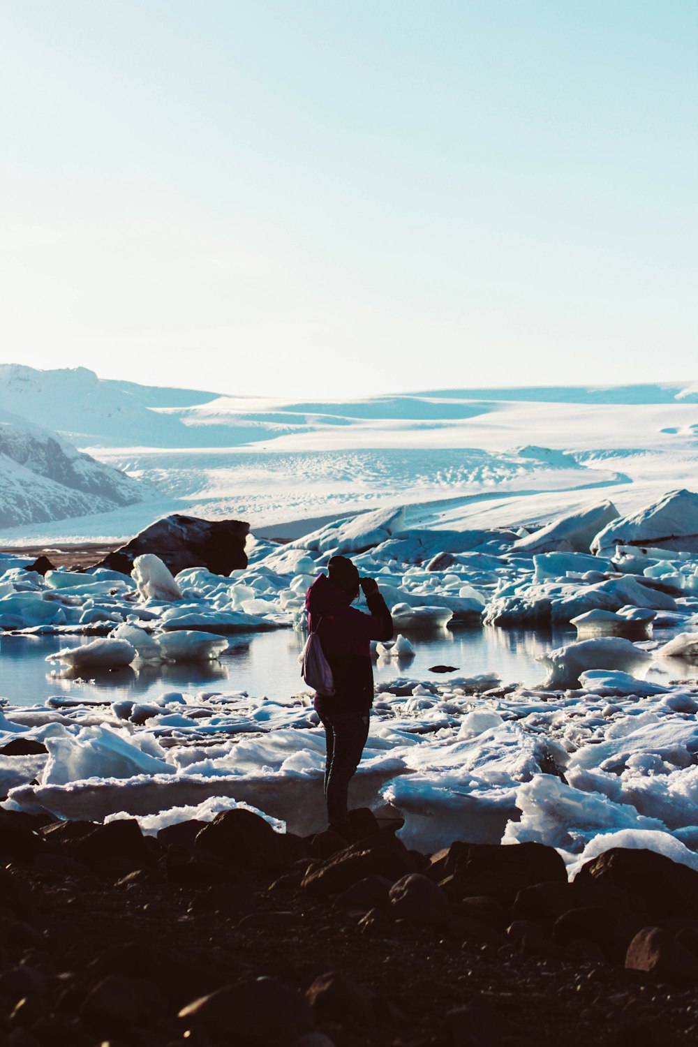 a person standing on a rocky beach next to a body of water