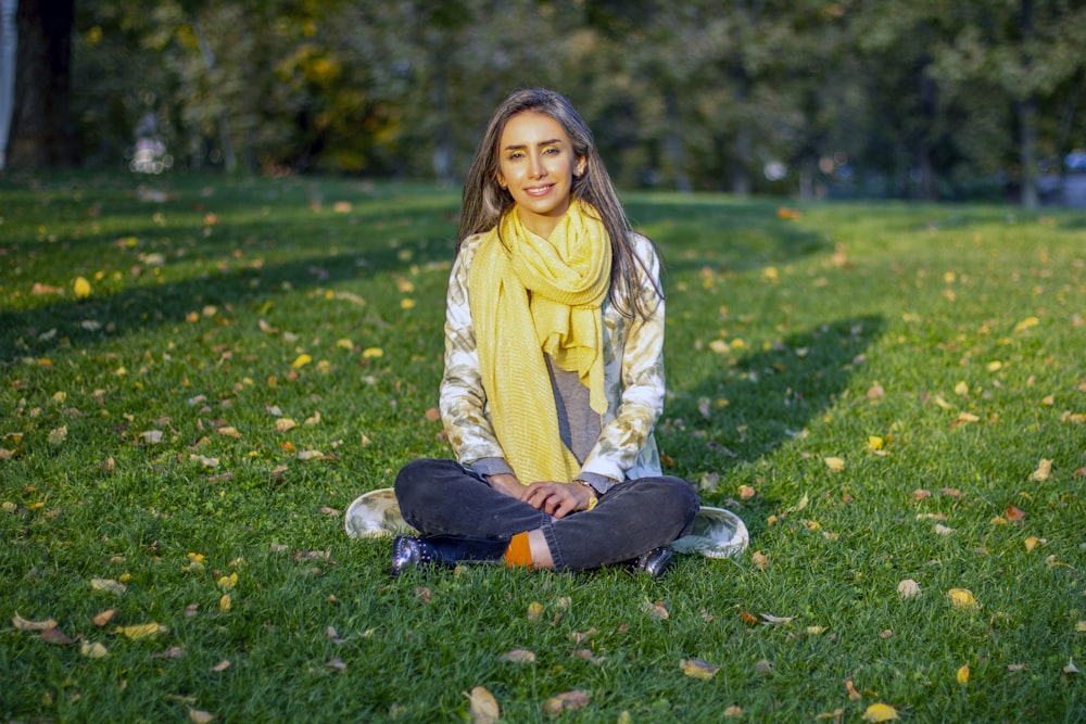 a woman sitting on the grass in a park