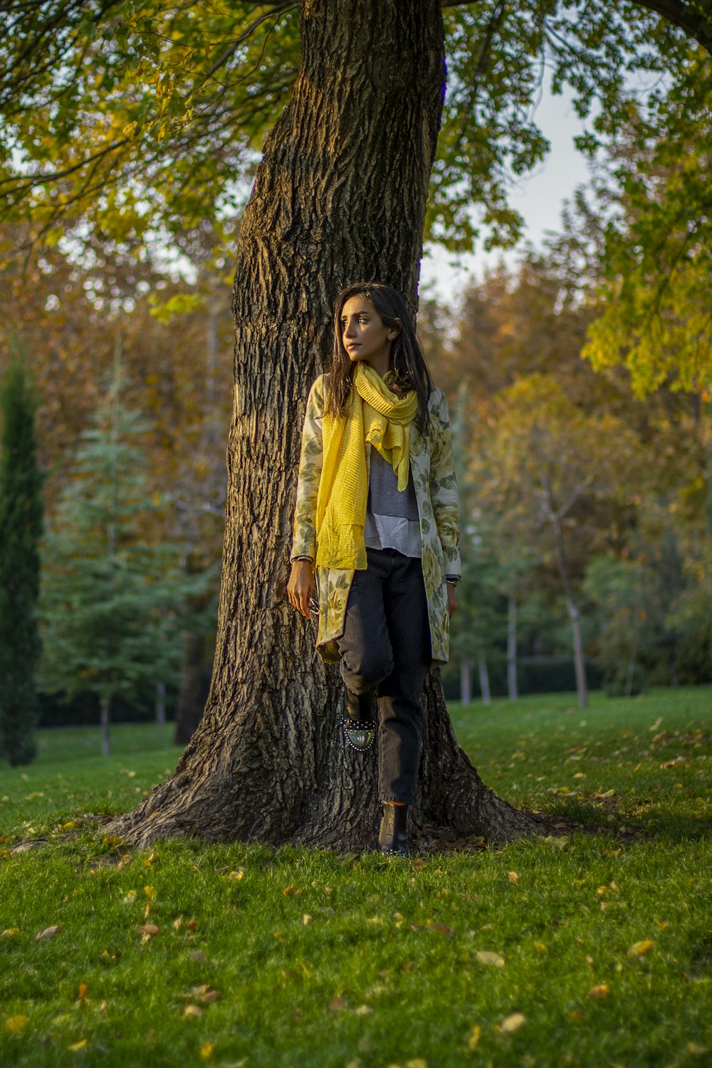 a woman standing next to a tree in a park