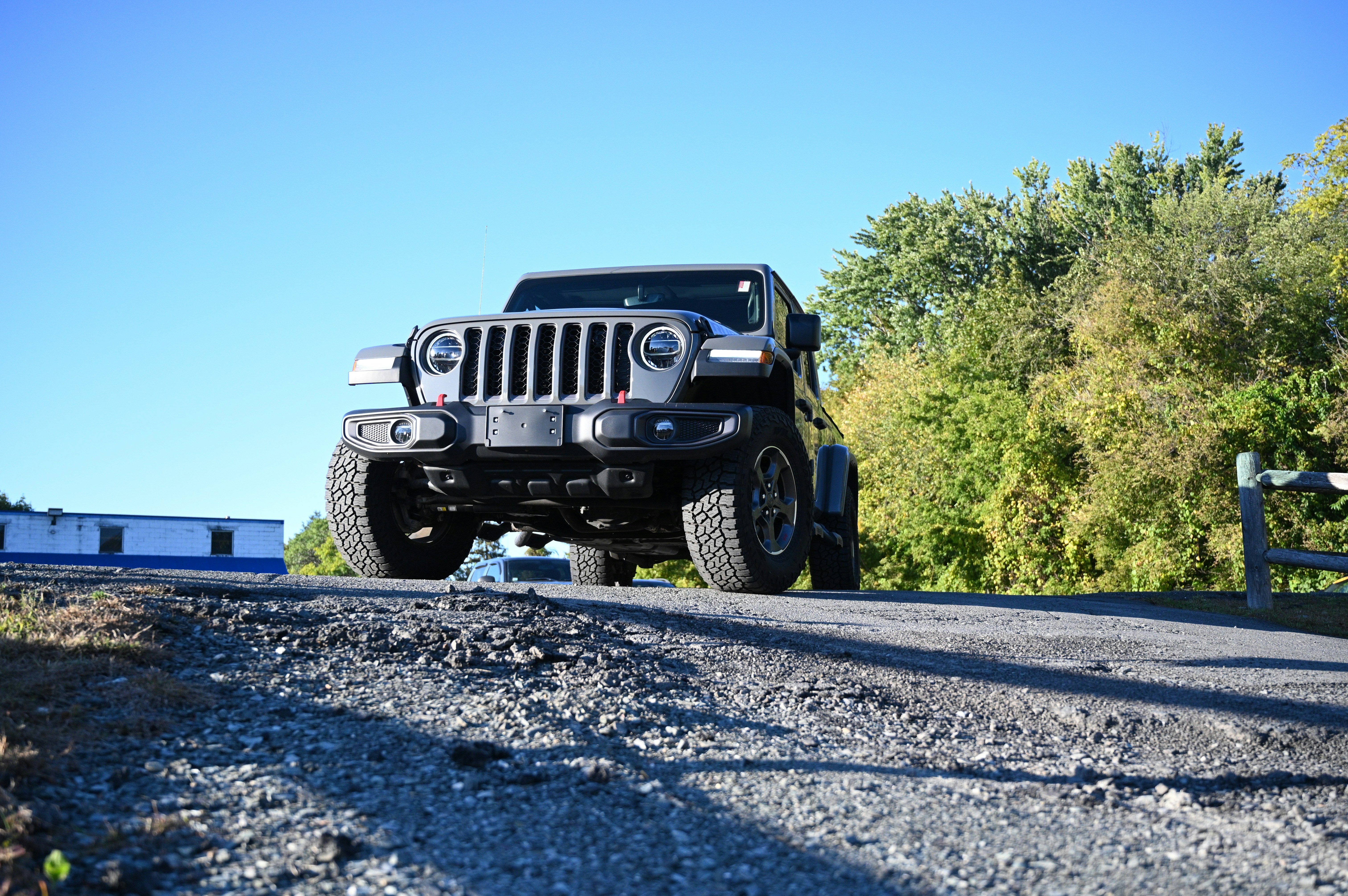 Une jeep noire roulant sur une route à côté d’une forêt