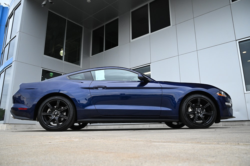 a blue sports car parked in front of a building