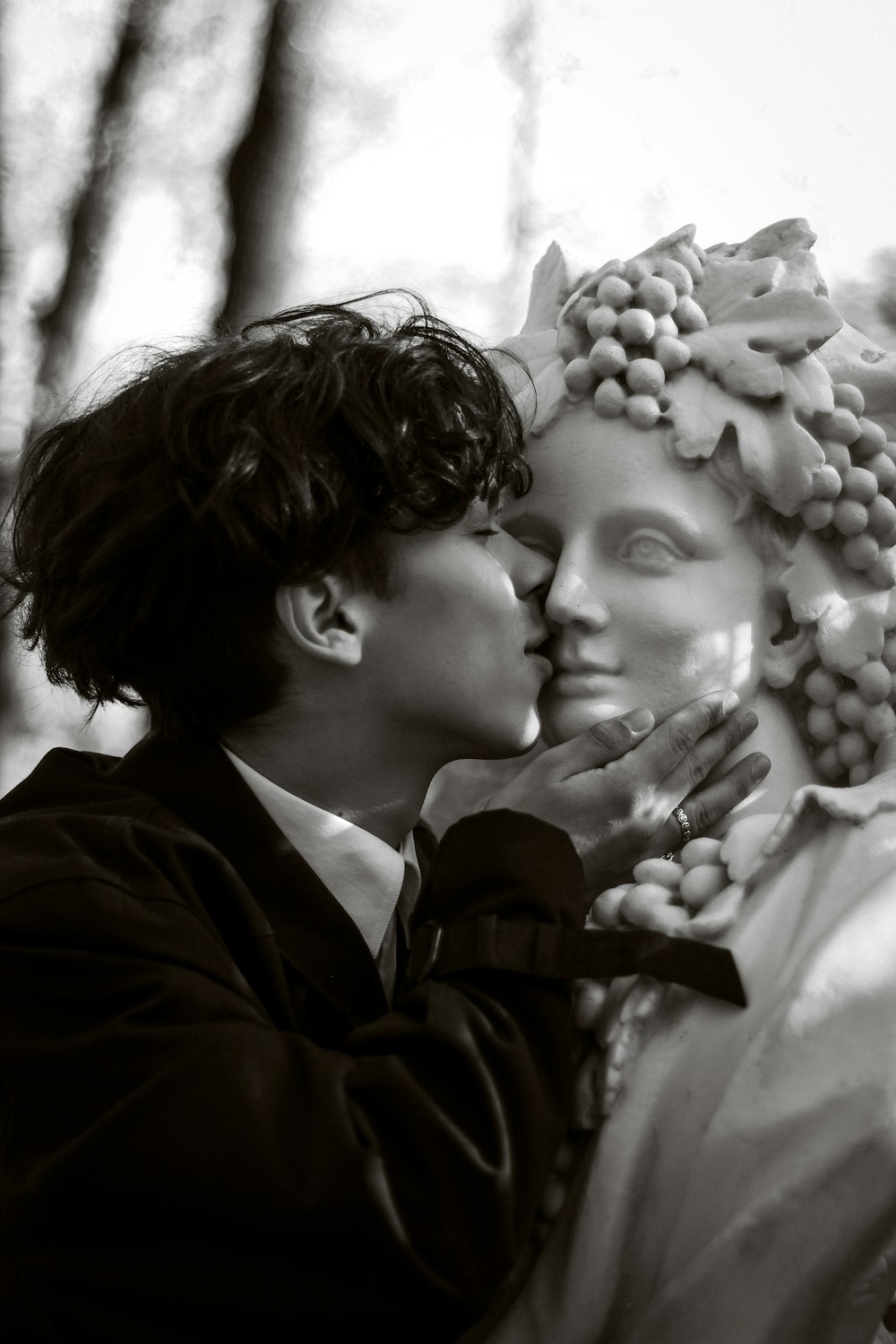 a man and a woman kissing in front of a statue