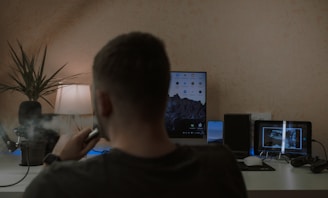 a man smoking a cigarette in front of a computer