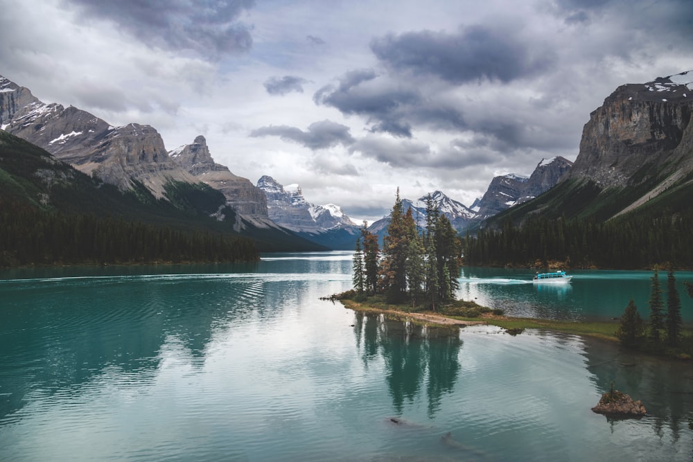 a lake surrounded by mountains under a cloudy sky