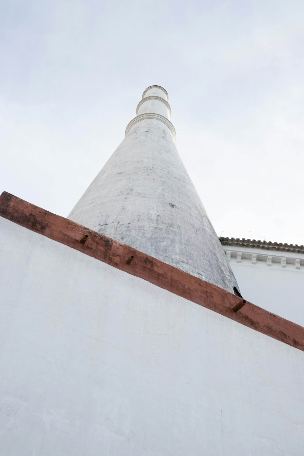 a tall white building with a brown roof