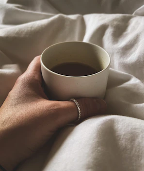 Artistic shot of a coffee-themed bracelet next to a steaming cup.