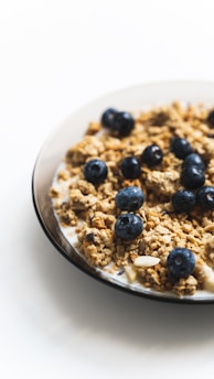 a white plate topped with granola and blueberries