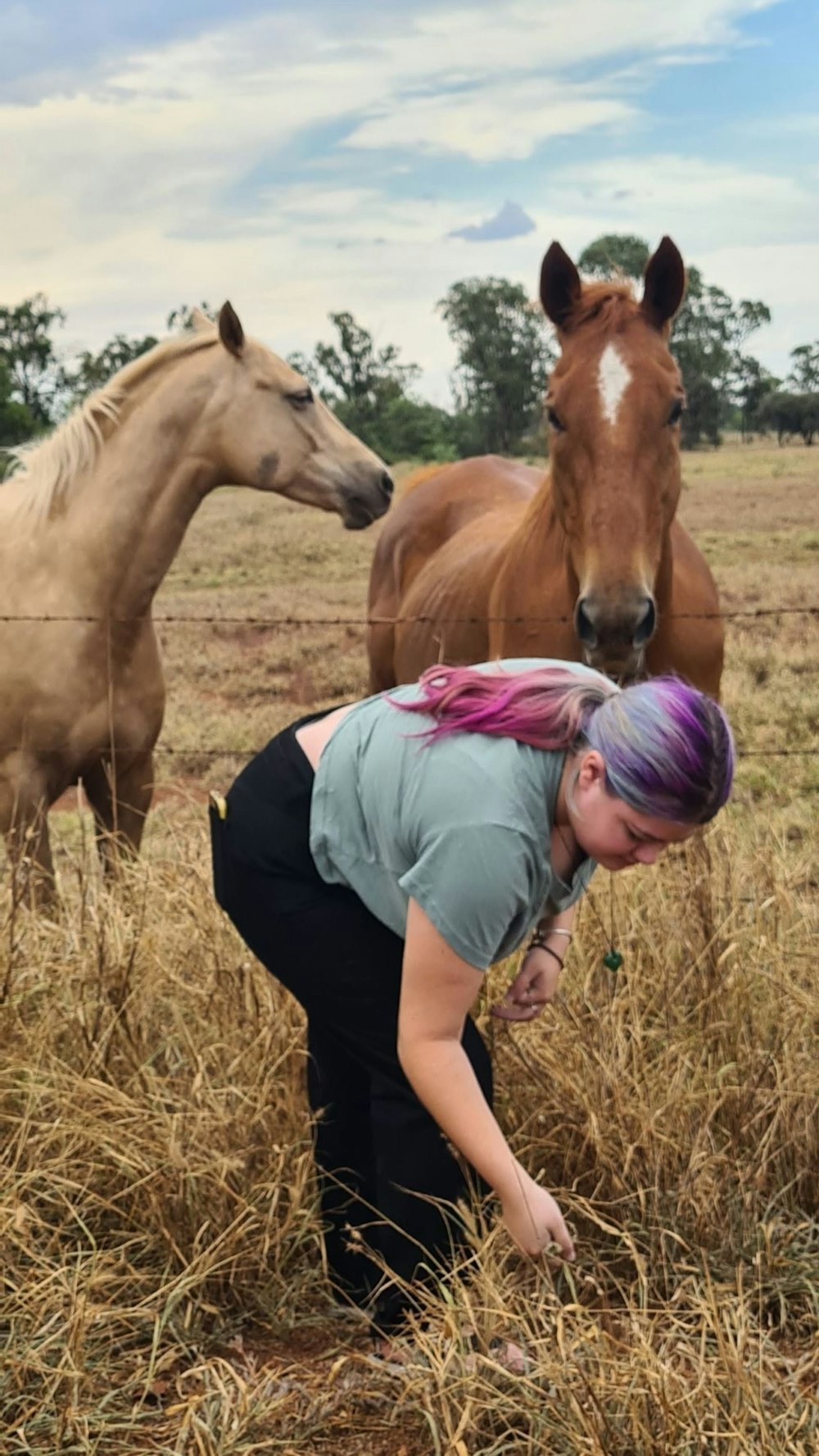 a woman bending down to pet a horse