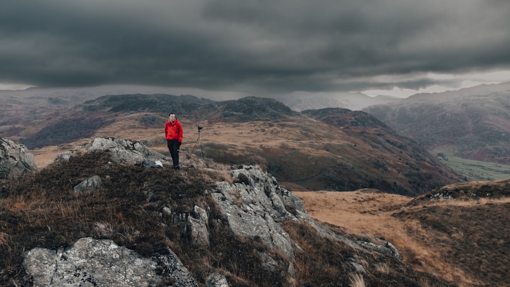 um homem em uma jaqueta vermelha de pé no topo de uma montanha