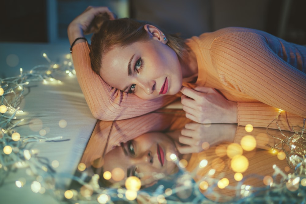 a woman laying on top of a bed covered in christmas lights