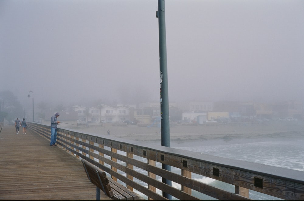 a person standing on a boardwalk near the ocean