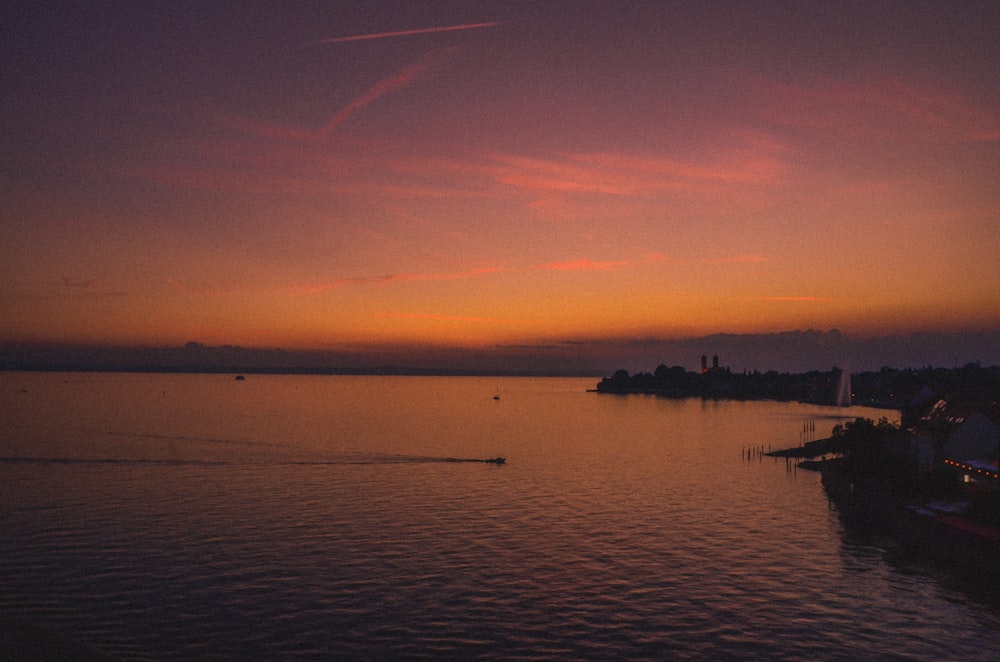 a sunset over a body of water with a boat in the water