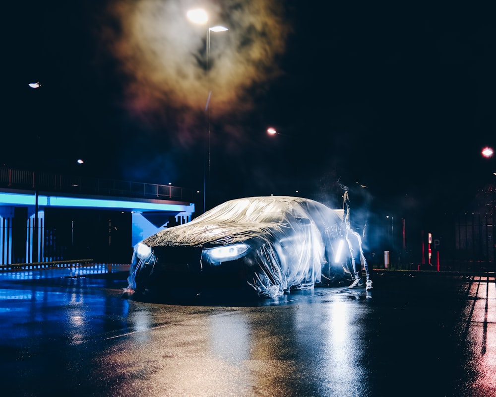 a car covered in a tarp on a rainy night