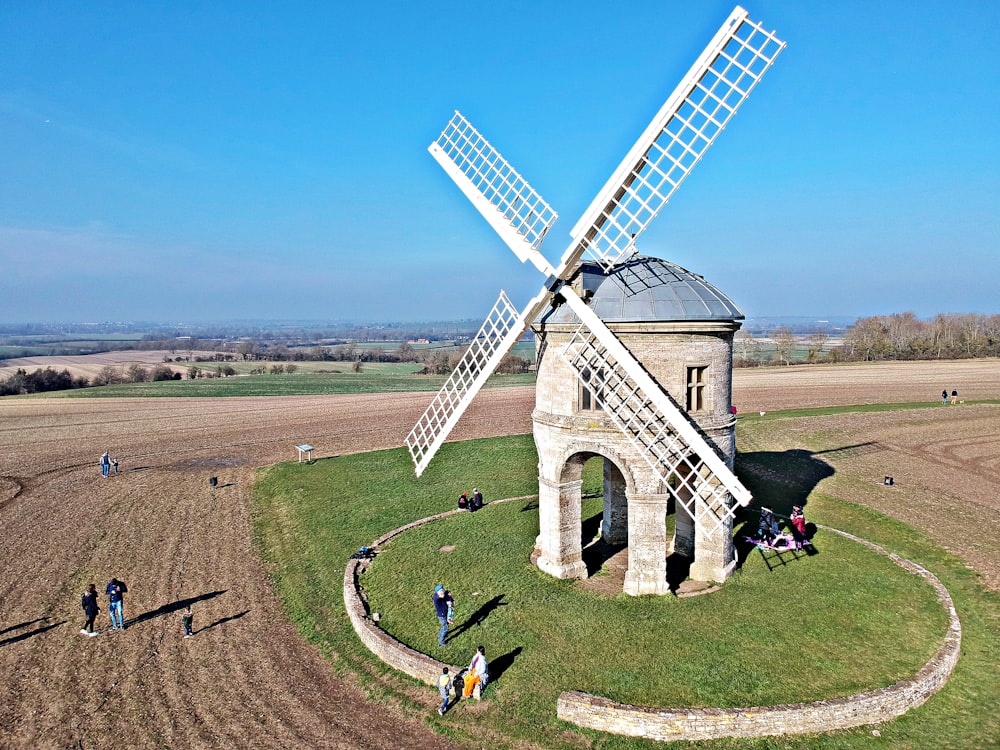 a group of people standing around a windmill in a field