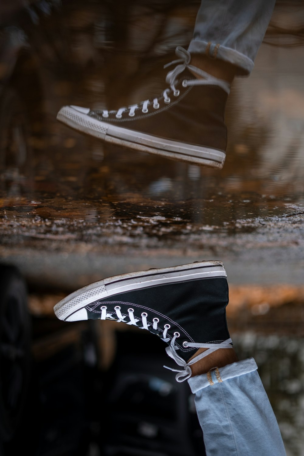 a pair of black and white sneakers are reflected in a puddle