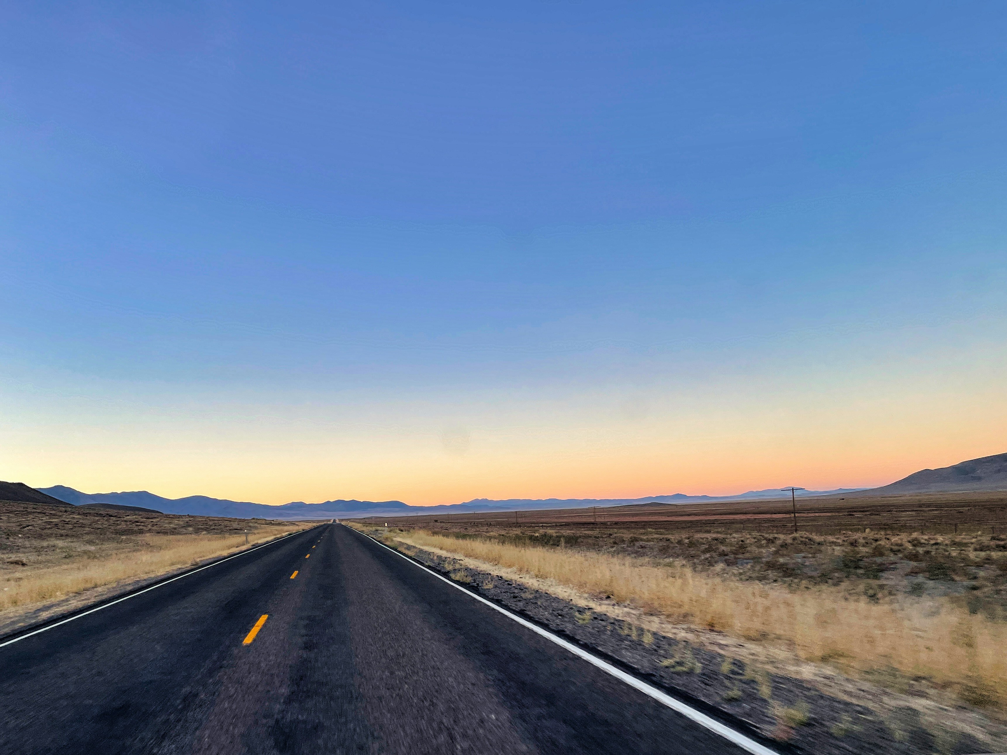 Open highway at dusk, long road stretching into distance, atmospheric low-light