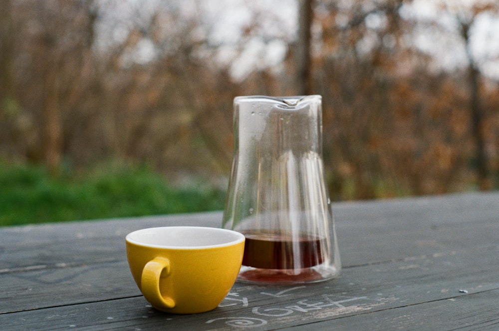 a pitcher and cup sitting on a wooden table