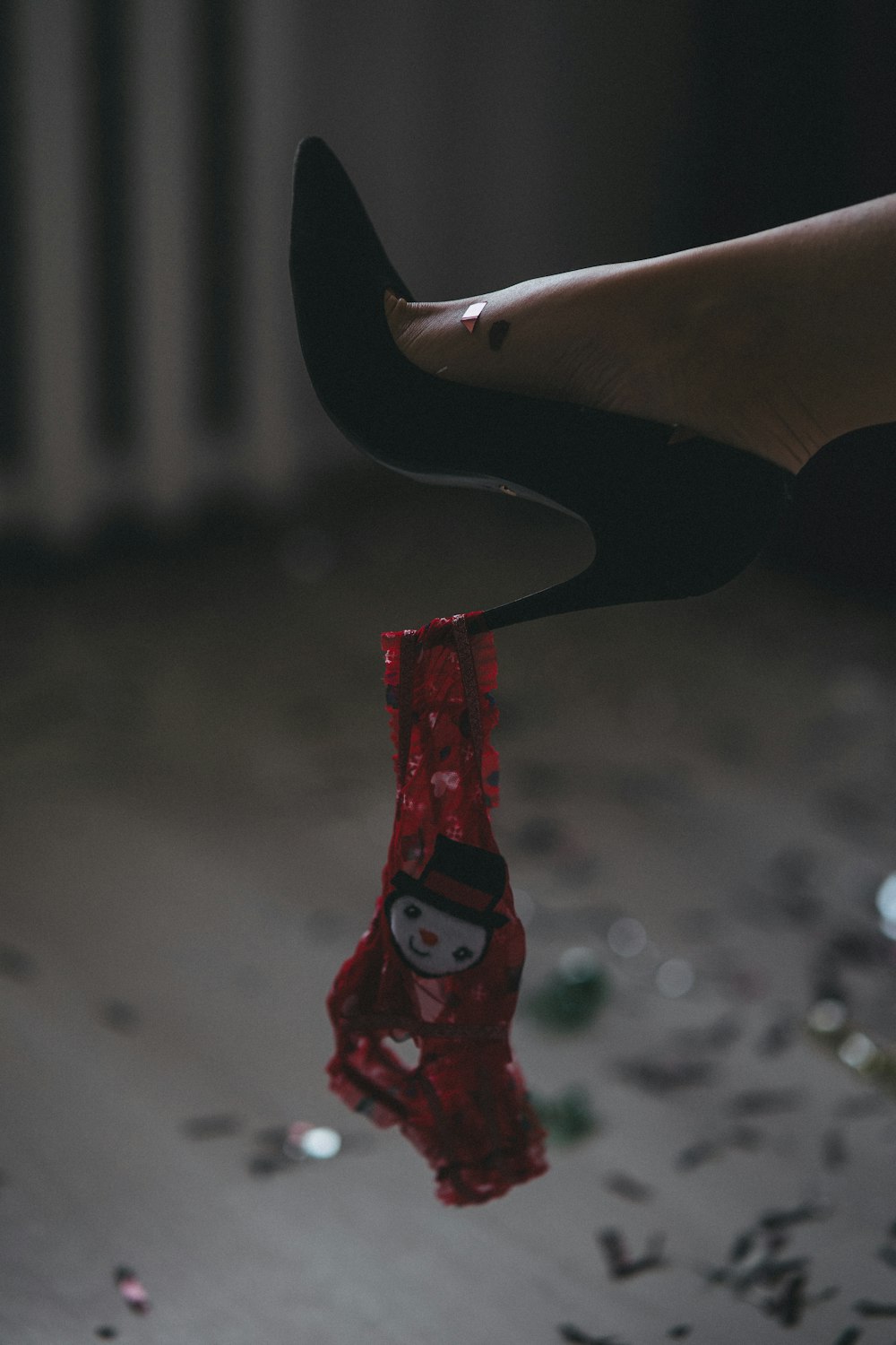 Piedi di una donna con una scarpa rossa appesa a una corda
