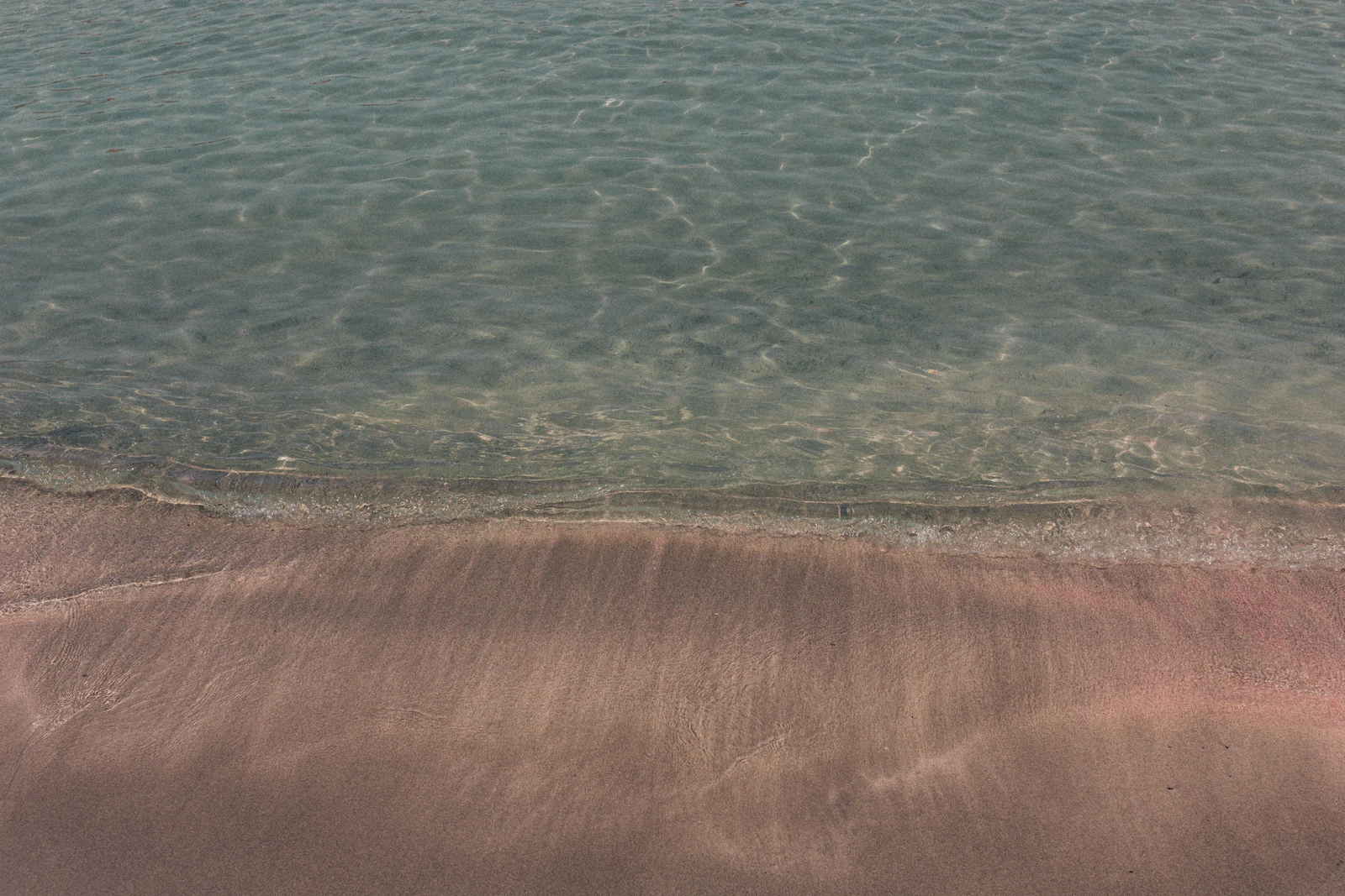 Close-up of the pink-tinged sand and clear water at Elafonisi beach, Crete, Greece