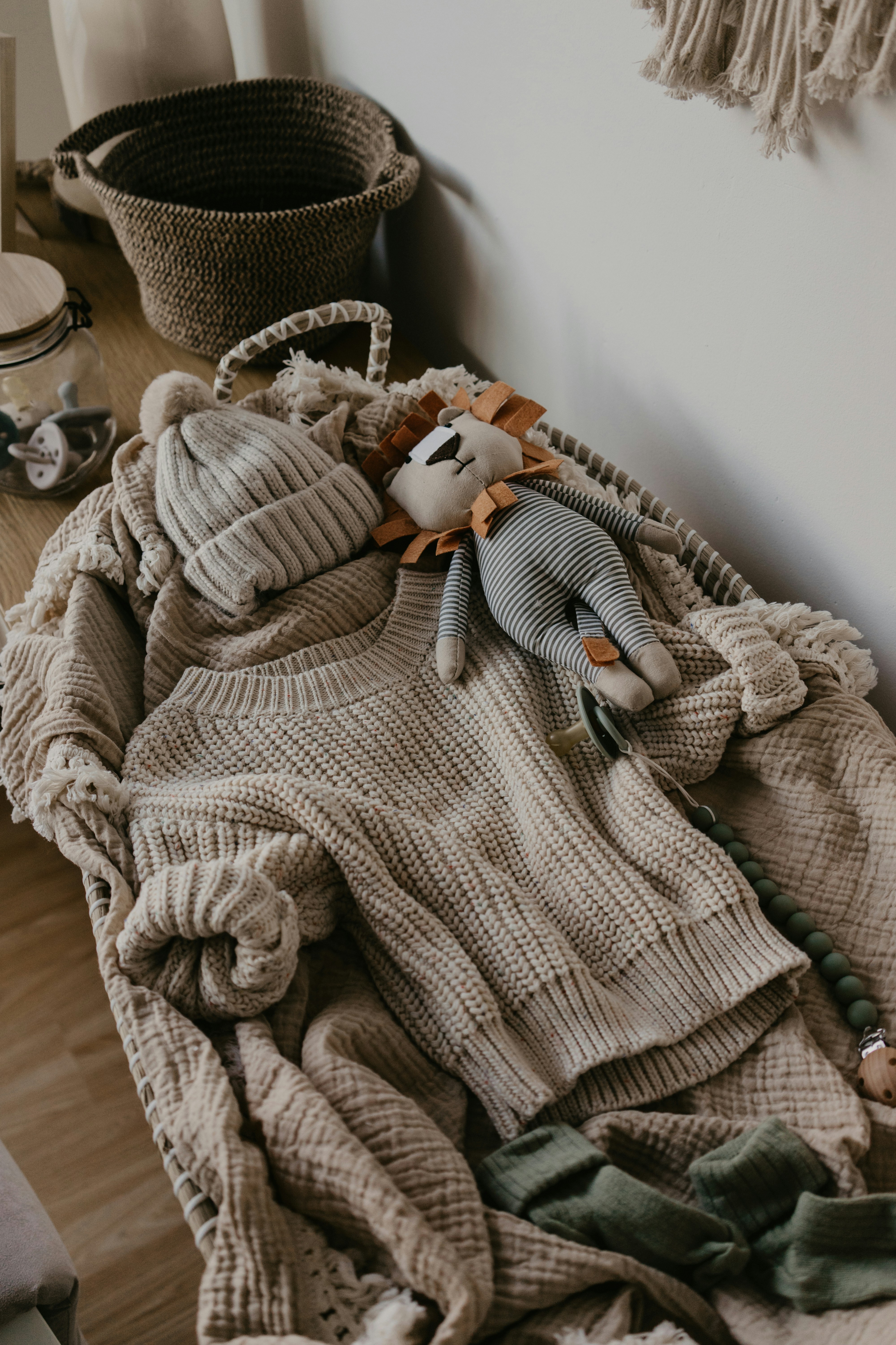 a pile of sweaters and a stuffed animal on a bed