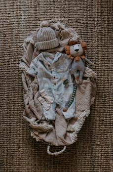 a teddy bear laying on top of a pile of clothes